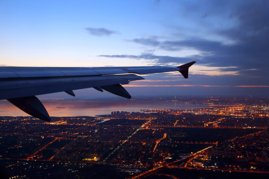 Airplane wing over city at dusk