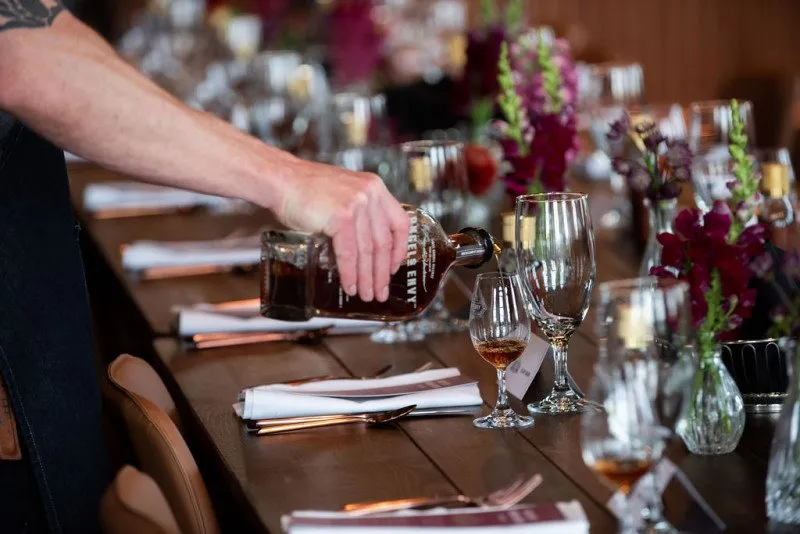 Hand pours bourbon into tasting glass at Angel’s Envy